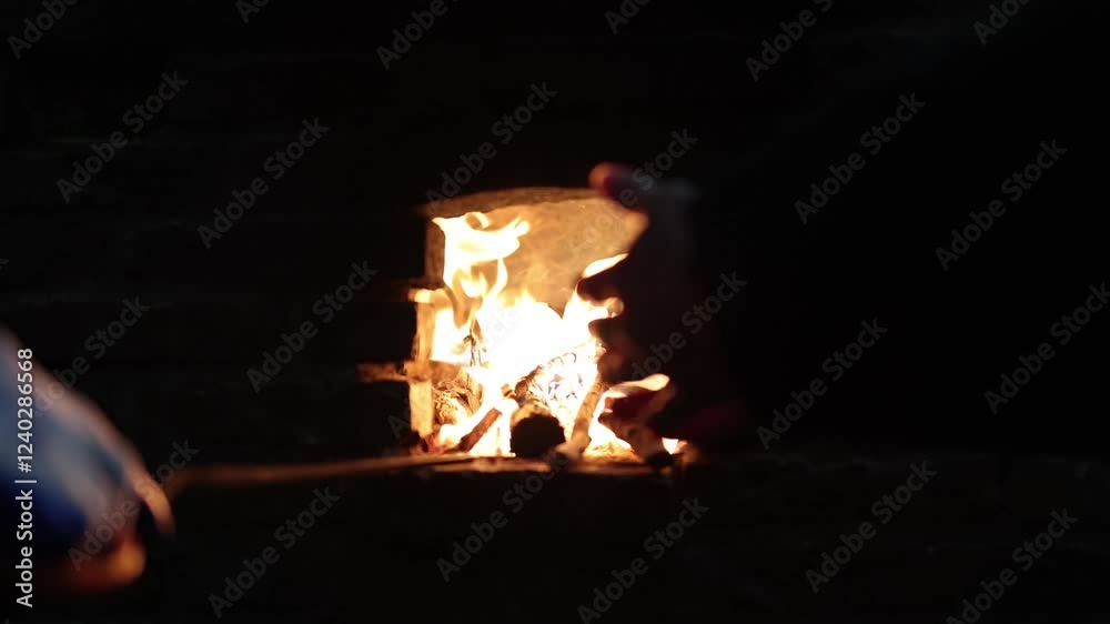 Hands reaching toward bright flames in a cozy fire setting at night near a rustic fireplace Hands reaching toward bright flames in a cozy fire setting at night near a rustic fireplace