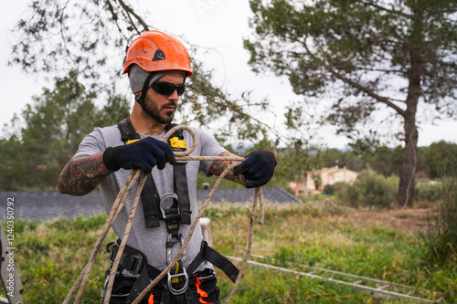 Rope access technician preparing equipment for tree pruning