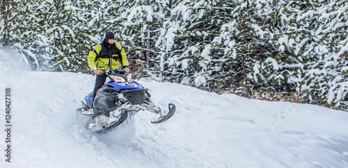 Big blue sport snowmobile jump. Guy is flying and jumping on a snowmobile on a background of winter forest. Man action snowmobile jumping. Jumping on a snowmobile on a background of winter forest photo