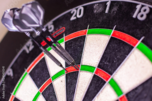 Dartboard with closeup view of three darts sticking in the Triple 20