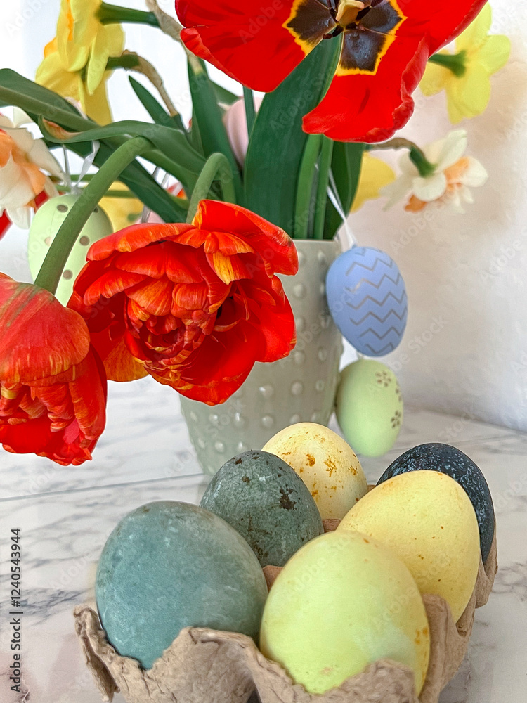 Bright colorful eggs are packed on the table next to a bouquet of tulips. An Easter card. Close. Vertical photography