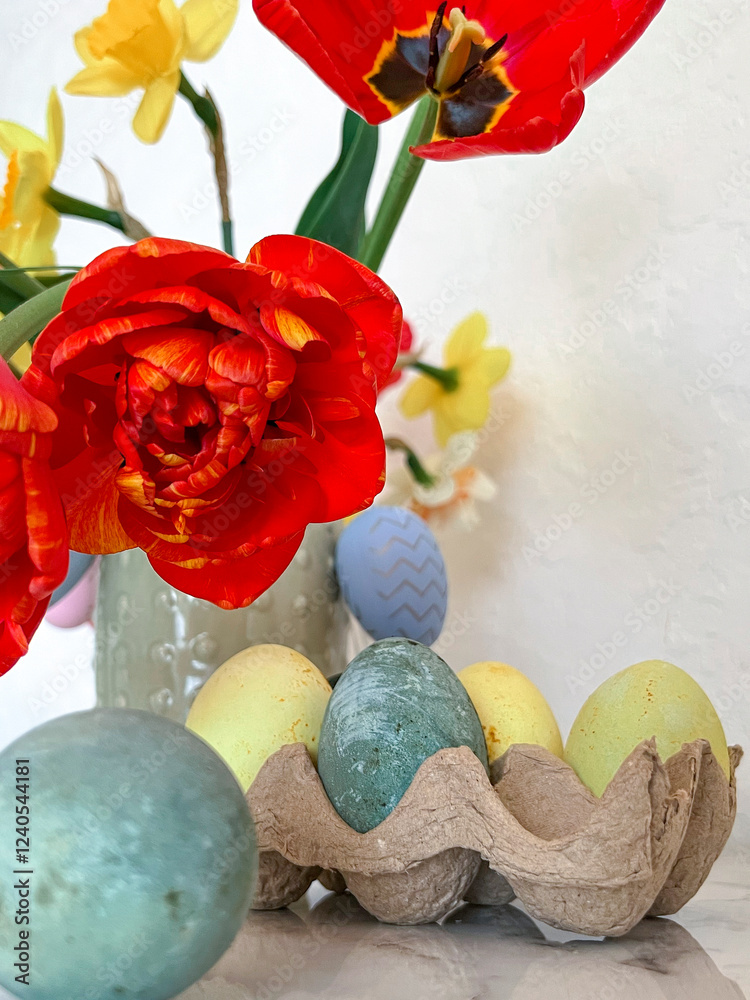 Bright colorful eggs are packed on the table next to a bouquet of tulips. An Easter card. Close. Vertical photography