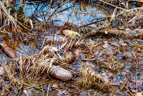 Various kinds of trash waste objects a lot floating in the pond mixed with aquatic plants