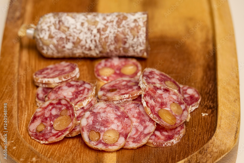slices of fuet salami with walnuts on a wooden chopping board slices of fuet salami with walnuts on a wooden chopping board