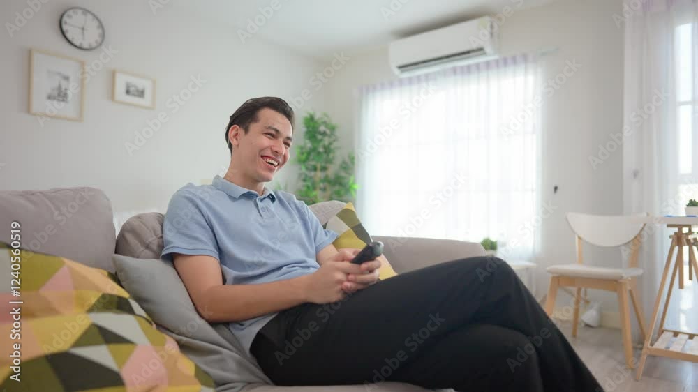 Asian handsome man watching funny movie on television in house. Asian handsome man watching funny movie on television in house.