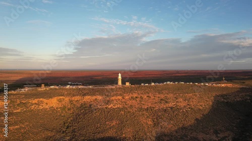 Aerial view of vlamingh head lighthouse amidst rugged landscape and tranquil sunset, exmouth, australia. photo