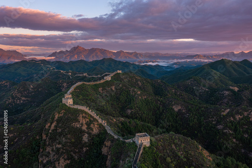 Aerial view of the majestic Jinshanling Great Wall amidst serene mountains and a colorful sunset sky, Chengde, China. photo