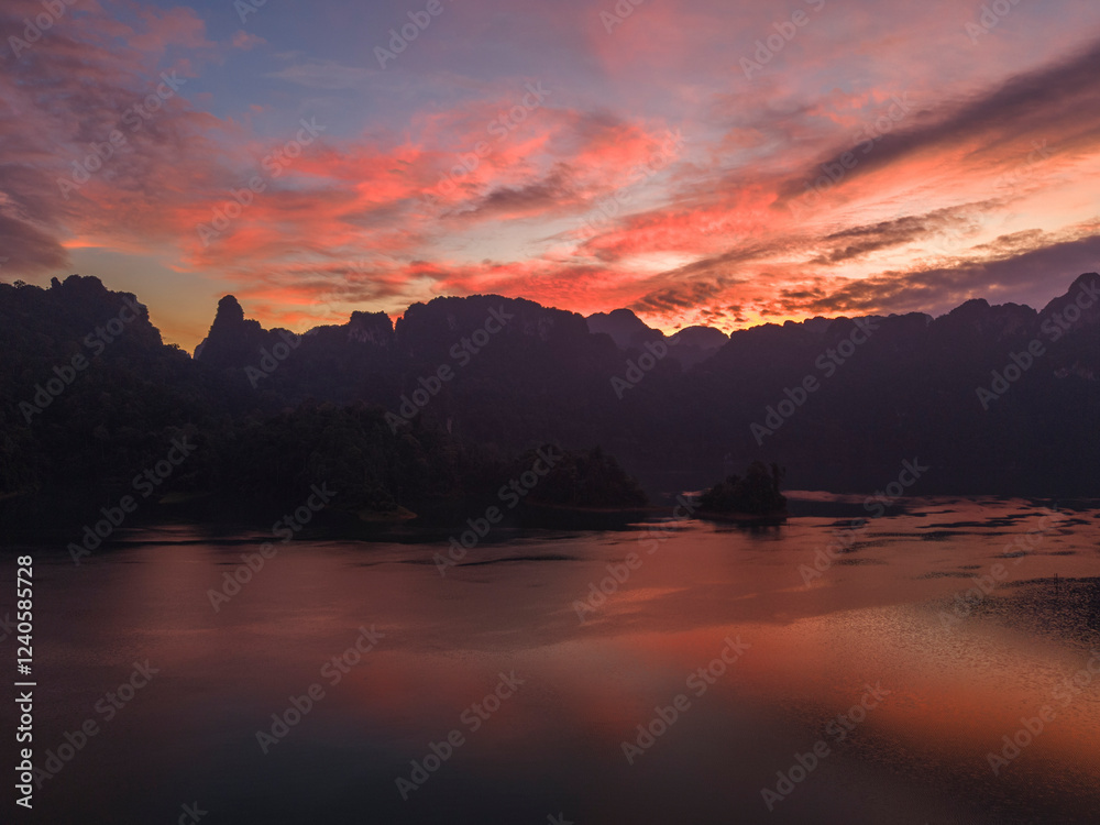 Aerial view of cheow larn lake at sunrise surrounded by lush rainforest and majestic mountains, Ban Ta Khun, Thailand. Aerial view of cheow larn lake at sunrise surrounded by lush rainforest and majestic mountains, Ban Ta Khun, Thailand.