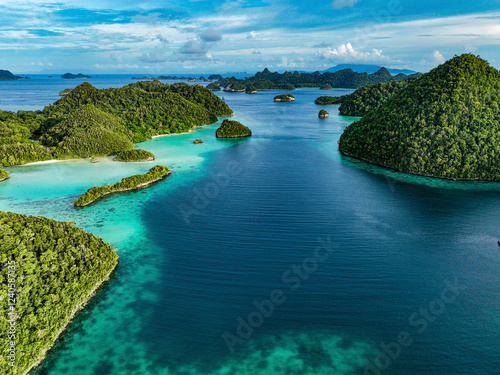 Aerial view of beautiful tropical islands and azure blue water in a serene lagoon, Raja Ampat Regency, Indonesia.