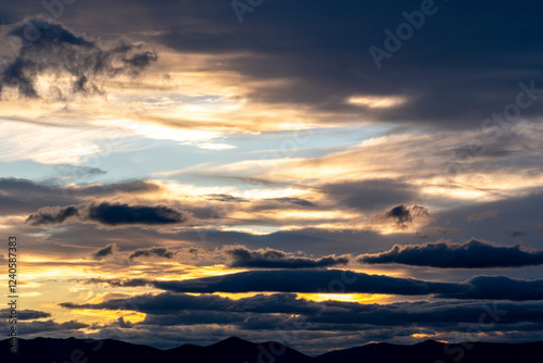 A stunning dusk view with the sun peeking through the clouds and mountains, evoking emotions of hope and tranquility amidst a beautiful sky-lit scene. photo