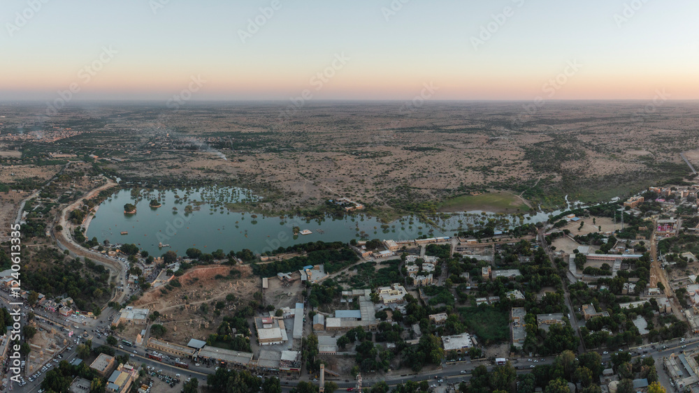 Aerial view of tranquil Amar Sagar Pol with serene lake and beautiful cityscape at dusk, Jaisalmer, Rajasthan, India. Aerial view of tranquil Amar Sagar Pol with serene lake and beautiful cityscape at dusk, Jaisalmer, Rajasthan, India.