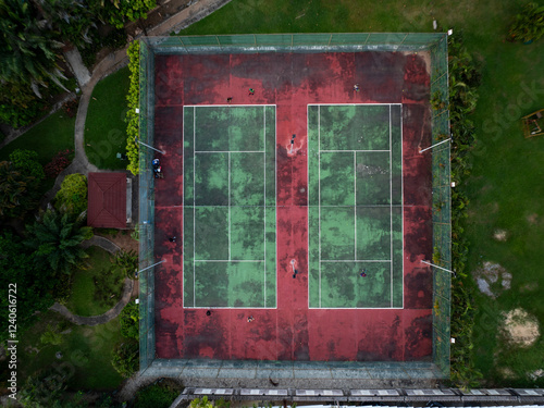 Aerial view of vibrant tennis courts with players in action surrounded by urban architecture and lush vegetation, Lagos, Nigeria. photo