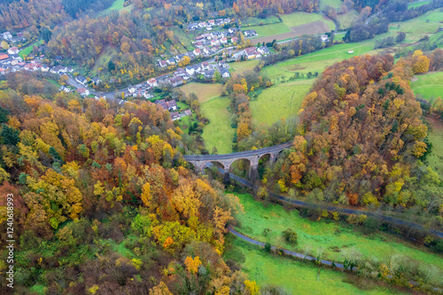 Aerial view of a beautiful autumn scene with a bridge surrounded by vibrant trees in a serene valley, Rimbach, Baden Wurttemberg, Germany. photo