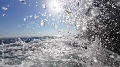 Side view of the sailing luxury yacht, foamy waves, and sunshine on the sea on a clear sunny day.