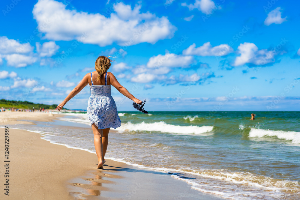 Beautiful middle aged woman tourist on beach holidays on sunny day. Back view Beautiful middle aged woman tourist on beach holidays on sunny day. Back view