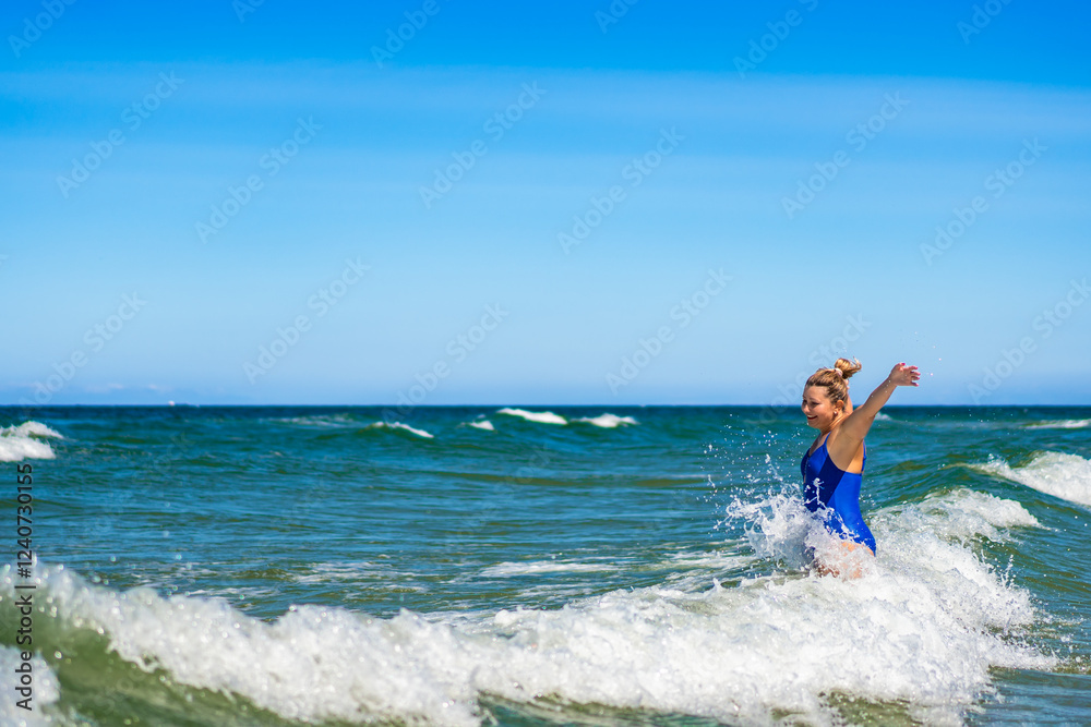 Beautiful mature woman enjoying bathing in big waves in sea in summertime Beautiful mature woman enjoying bathing in big waves in sea in summertime