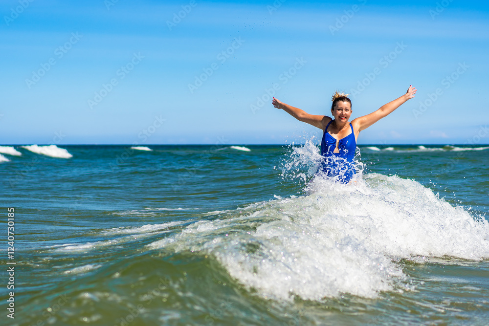Beautiful mature woman enjoying bathing in big waves in sea in summertime Beautiful mature woman enjoying bathing in big waves in sea in summertime