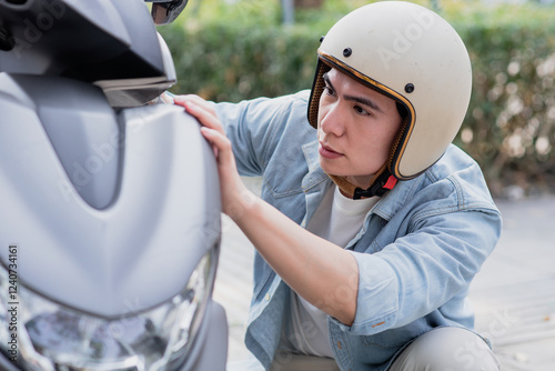 Asian man is checking his faulty motorbike
 photo