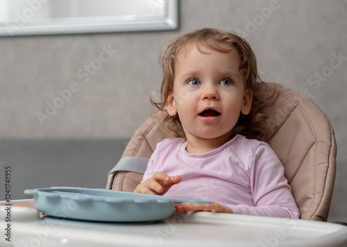 A surprised toddler showing excitement and curiosity during mealtime at home.