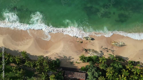 Huge turquoise waves breaking slowly on lonely sandy beach on Sri Lanka island near Tangalle town . Traveling or exotic asian countries aerial drone point view 4K rotating footage.