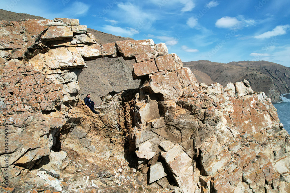 Fototapeta premium The girl in the stone arch in the rock. Hiking, the concept of freedom, outdoor activities, extreme sports.