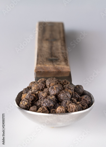 Obraz na płótnie Perspective view of Raw organic black peppercorns or Dry black pepper seeds in stainless steel spoon isolated on the white background. use it as your Space for text, Design, Wallpaper and Poster. w salonie