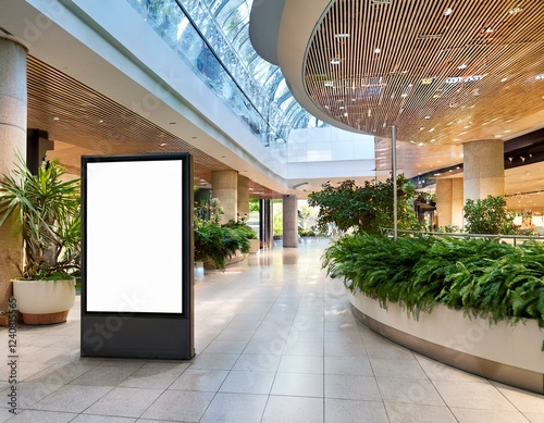 blank digital signage in a modern shopping mall surrounded by greenery