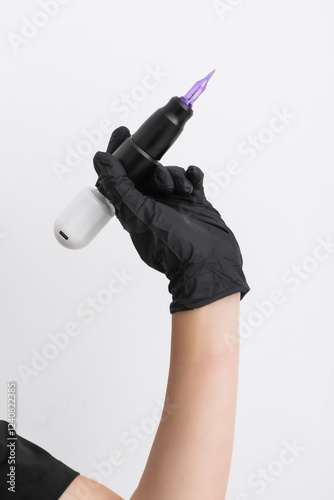 A wireless tattoo machine in the hand of a beauty salon specialist in eyebrow tattooing. Close-up of a female hand holding a tattoo gun