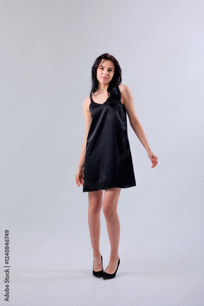 Elegant woman in a black dress standing confidently with high heels against a minimalistic backdrop Elegant woman in a black dress standing confidently with high heels against a minimalistic backdrop
