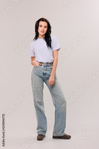 Woman in casual outfit poses confidently against a light background in a studio setting