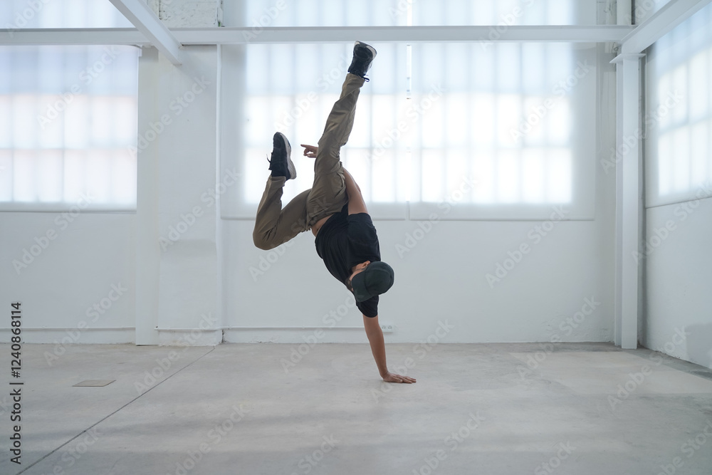 In a bright and spacious studio, a highly skilled breakdancer showcases their impressive dance talents In a bright and spacious studio, a highly skilled breakdancer showcases their impressive dance talents