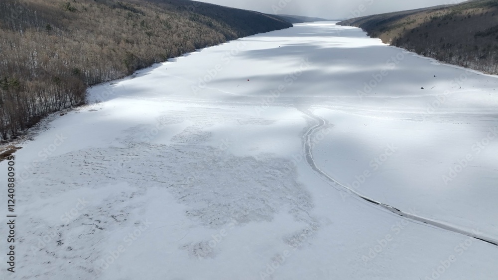 Obraz premium Ancient Glacier finger lake Hemlock Lake, NY during Winter in freezing conditions ideal for ice fisherman landscape with cloud shadows on snow covered lake