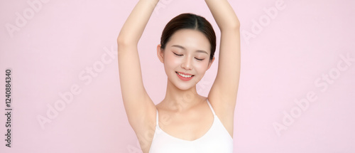 Beautiful Korean woman with flawless underarm skin posing confidently in a soft pink background photo