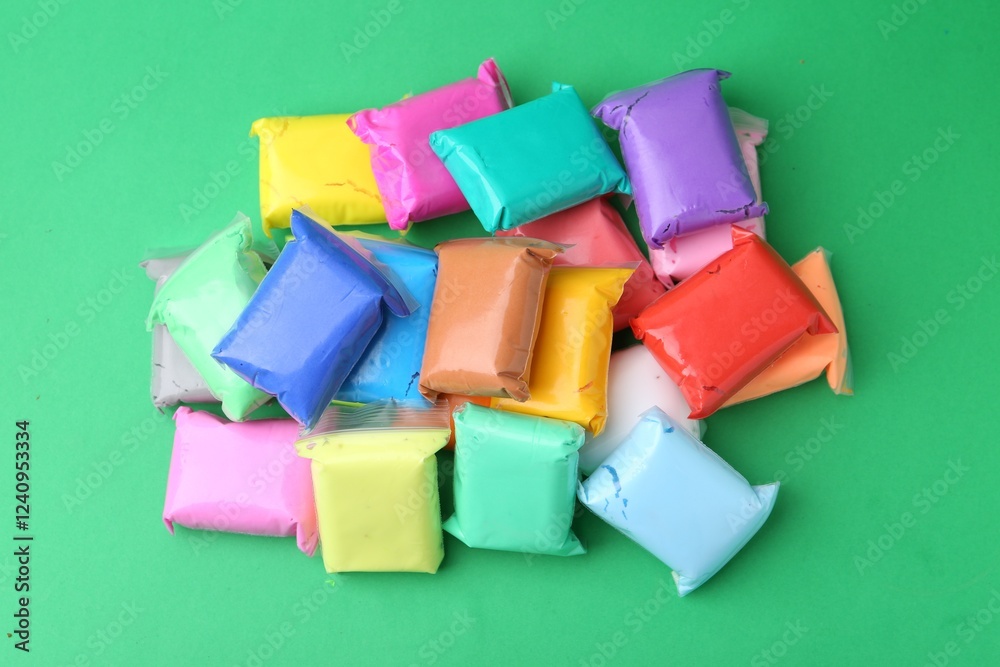 Different colorful play dough in packages on spring green background, top view Different colorful play dough in packages on spring green background, top view