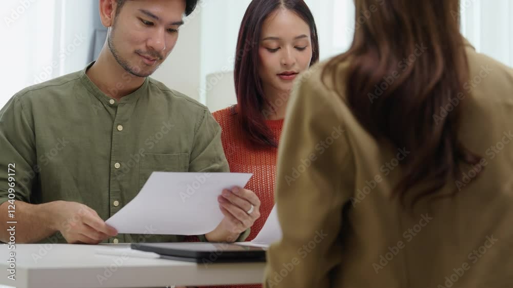 asian financial advisor presenting charts and data on a tablet during couple client meeting.financial planning and decision-making