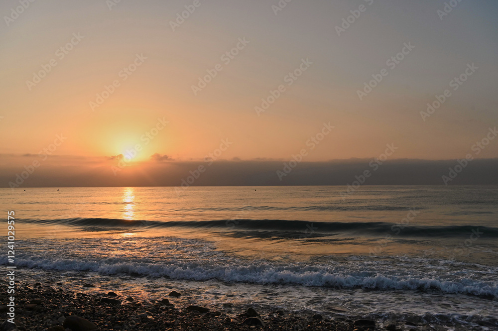 As the sun sets on the horizon, warm golden hues paint the sky while gentle waves kiss the pebbled shore, creating a tranquil evening at the beach. As the sun sets on the horizon, warm golden hues paint the sky while gentle waves kiss the pebbled shore, creating a tranquil evening at the beach.