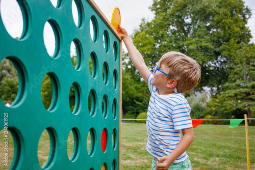 Boy plays giant Connect Four outdoors, enjoying the fun game