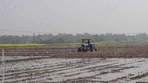 farmer plowing a paddy field with a tractor