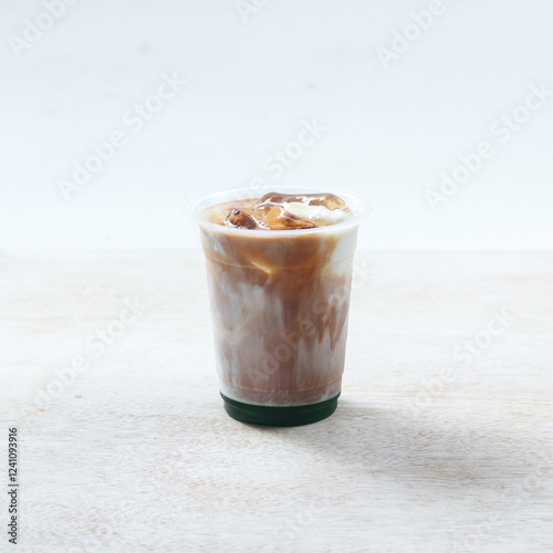 Iced pandan coffee, Iced coffee is featured in a clear cup filled with ice on a smooth surface, capturing the essence of a warm, sunny afternoon photo