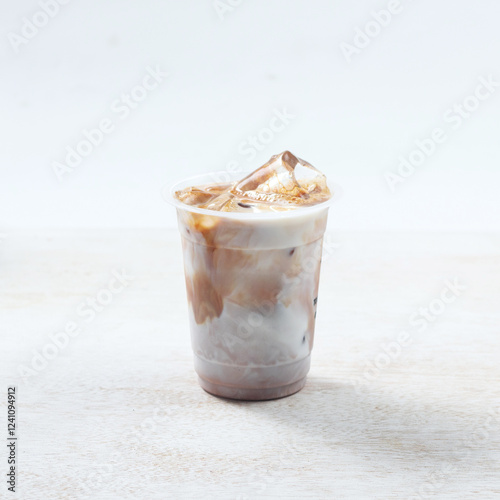 Iced coffee latte, Iced coffee features creamy layers and ice, showcasing a delightful mix of flavors in a clear cup against a neutral backdrop