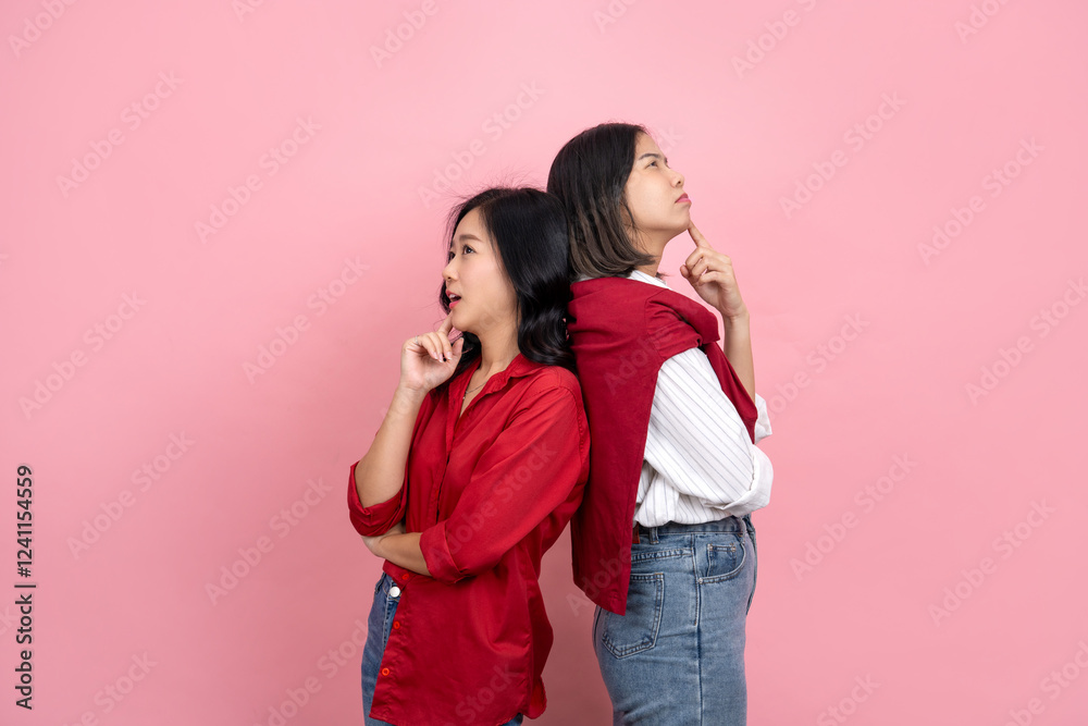 Two young Asian girls are thinking and touching their chins while looking over something. Isolated on a pink background. Two young Asian girls are thinking and touching their chins while looking over something. Isolated on a pink background.
