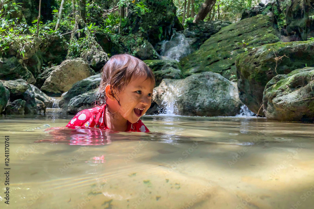 little asian girl playing by the waterfall with a heart full of laughter.