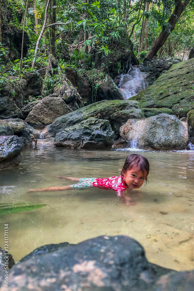 little asian girl playing by the waterfall with a heart full of laughter.