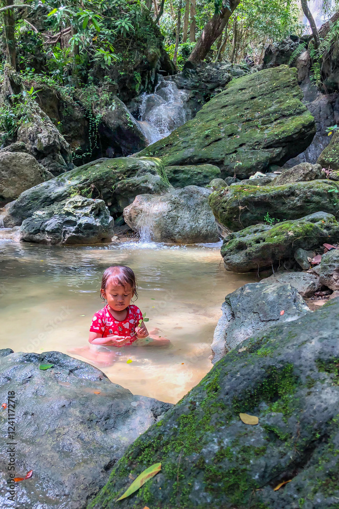 little asian girl playing by the waterfall with a heart full of laughter.
