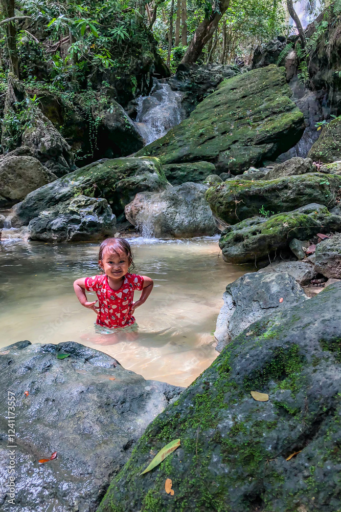 little asian girl playing by the waterfall with a heart full of laughter.