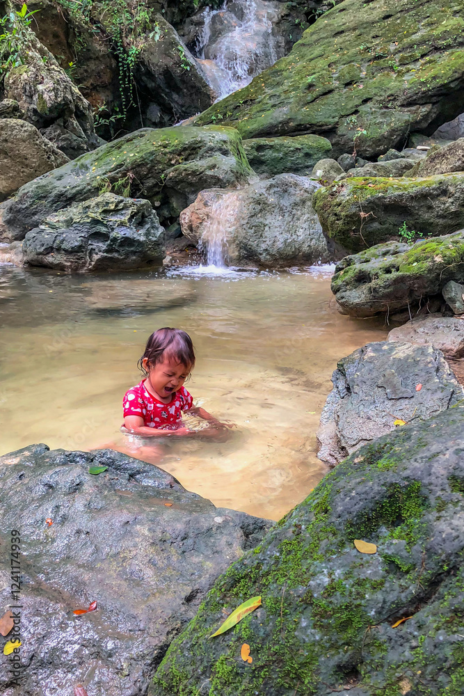 little asian girl playing by the waterfall with a heart full of laughter.
