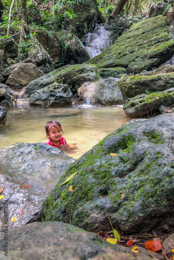 little asian girl playing by the waterfall with a heart full of laughter.