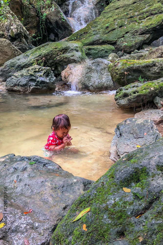 little asian girl playing by the waterfall with a heart full of laughter.