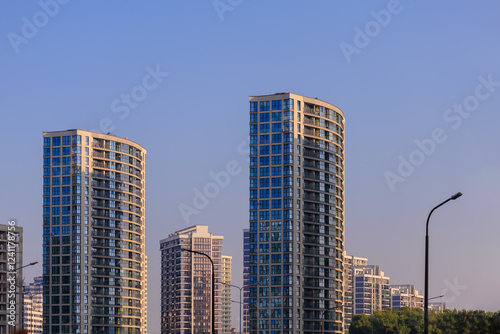 Modern buildings, walls and windows, reflections and sun rays. City view on a sunny day. 
