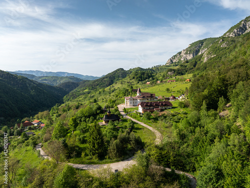 Sub Piatra Monastery nestled in lush green hills with mountain views, representing tranquility and spiritual retreat. Monastery in Apuseni Mountains, Transylvania, Romania. photo